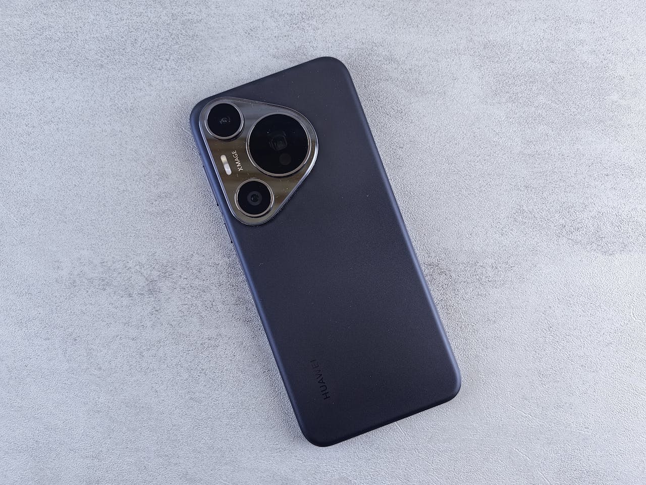 Flat lay of a modern smartphone with a sleek camera design on a textured surface.
